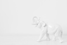 White Elephant On A White Background. Porcelain Elephant Figurine On The Table