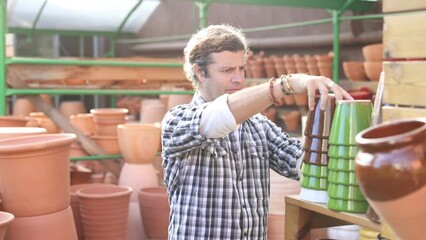 Wall Mural - European man who came to the horticultural market carefully chooses flower pots for indoor plants, examines them. 