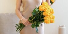 Young Woman With Beautiful Yellow Roses In Room, Closeup