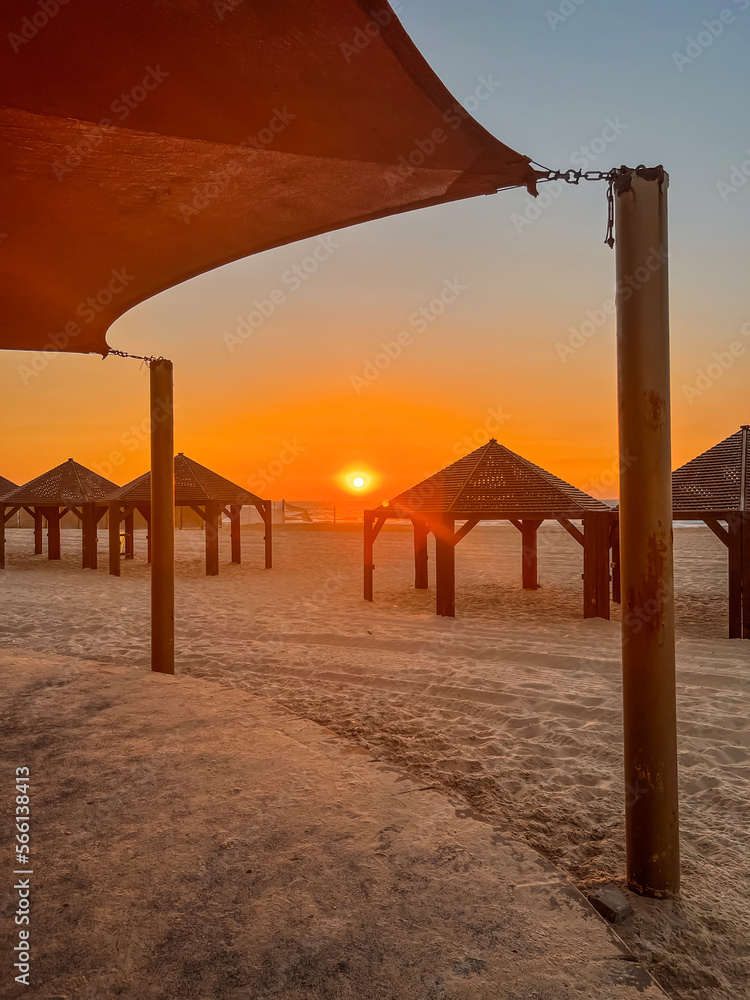 View of sea beach with gazebos at sunset