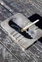 Lit Joint In A Metal Ashtray With Hard Light And Shadows And A Rusty Look