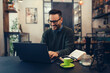 © zorandim75 - Handsome young man in eyeglasses is using laptop and smiling while sitting in cafe