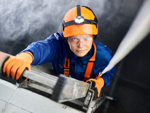 Industrial Worker Wearing Hard Hat And Climbing Harness Ascending Ladder