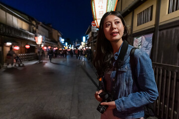 Wall Mural - smiling asian Japanese girl visitor looking into space with curiosity while visiting geisha district on hanamikoji street in gion Kyoto japan at nighttime