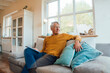 © Westend61 - Senior man with tablet PC sitting on sofa in living room at home