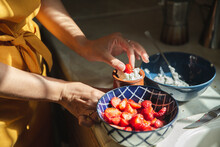 Hands Of Woman Dipping Strawberries In Cream At Kitchen