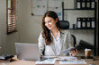 © Nuttapong punna - Asian businesswoman working in the office with working notepad, tablet and laptop documents