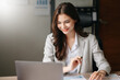 © Nuttapong punna - Young beautiful woman typing on tablet and laptop while sitting at the working wooden table  office