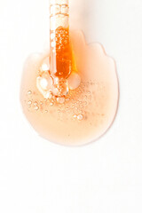 Canvas Print - Cosmetic dropper pipette with drops of product on the whte background of golden smear with bubles.