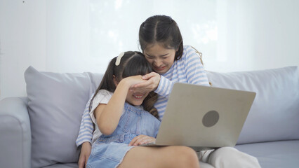 Portrait of Asian Family. A student watching scary movie on computer device online at home or house in family relationship. People lifestyle. Education activity