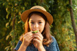 © _KUBE_ - Exotic fresh fruit. Close up portrait of cute little girl in a straw hat eating a passion fruit. Concept of organic gardening and home agriculture