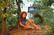 © _KUBE_ - Country summer. Cute caucasian little girl wearing straw hat sits on the ground in garden. The concept of local farming and psychology
