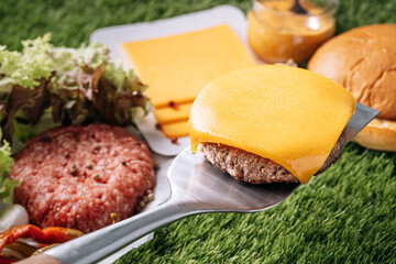 Wall Mural - barbecue burger cutlet. barbeque concept in nature. barbecue spatula with a burger patty on it