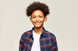 Portrait of charismatic positive good african american teen boy kid in plaid flannel shirt with toothy smile and afro hair, isolated against gray studio background. Happy teenagers