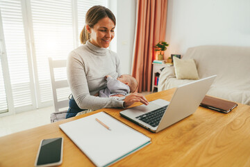 Young mother working at home while feeding her infant son - Smart working and family concept - Focus on mom face