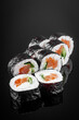 futomaki sushi roll with cucumber salmon cream cheese on a black mirror background