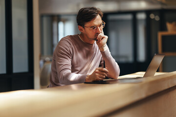 Wall Mural - Thoughtful web designer working with a laptop in a coworking office