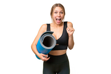 Wall Mural - Blonde sport woman going to yoga classes while holding a mat over isolated chroma key background celebrating a victory in winner position