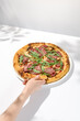 Woman take piece of italian pizza on white background. Female hand holding pizza with roastbeef. Trendy menu concept with italian pizza. Woman hand with food