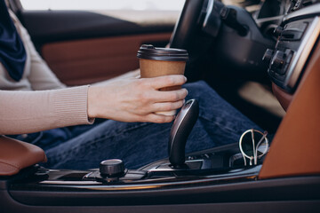 Female hands holding coffee cup in the car