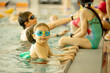 © Tomsickova - Child, taking swimming lessons in a group of children in indoor pool