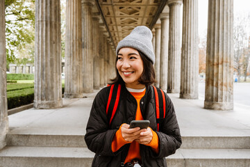 Wall Mural - Asian woman using smartphone during walk at city street