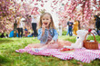 preschooler girl in tutu skirt enjoying nice spring day in cherry blossom garden