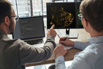 Closeup of two men data science specialists working at office together, analyzing big data on screen. Coders working on new project 