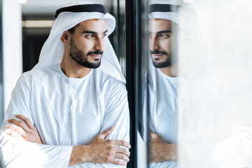 Wall Mural - handsome man with dish dasha working in his business office of Dubai. Portraits of a successful businessman in traditional emirates white dress. 