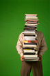 © Valente - man carrying a stack of books isolated on green background, stacked books, space for text