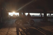© perfectlab - Young couple kissing sitting on a motorcycle in underground parking garage On the Sunset