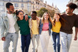 © Gigi Delgado - Happy international group of friends walking in the city street laughing. Cheerful young people hanging outside, embracing together. Concept of colleagues having fun outdoors. Front view.