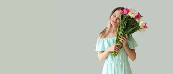 Poster - Pretty young woman with bouquet of beautiful tulips on light background with space for text