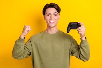 Wall Mural - Photo of positive overjoyed man wear khaki stylish clothes raise hands fists yes hooray win competition isolated on yellow color background