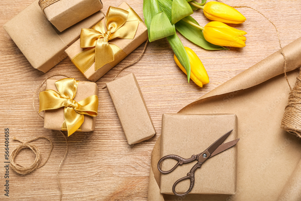 Composition with gift boxes, wrapping paper, rope, scissors and tulip flowers on wooden background. Women's Day celebration