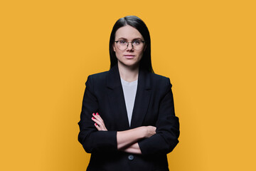 Confident business young female looking at camera on yellow background