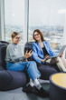 © Дмитрий Ткачук - Two young female freelancers working remotely in the lounge area at a laptop. The concept of remote work. Friendly relations between colleagues