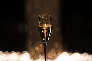 Glass of champagne with bubbles on dark background with bokeh. Celebration and party concept. 