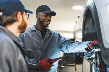 Mechanic wearing uniform fixing car tyres using an air wrench in a car service shop. High-quality photo