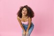 © SHOTPRIME STUDIO - Woman with curly afro hair model poses on a pink background in a pink T-shirt, free movement and dance, look into the camera, smile with teeth and happiness, copy space