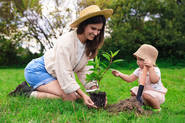 Mother and her baby daughter planting tree together in garden