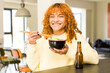 © kues1 - young red hair latin pretty woman eating ramen noodle bowl at home