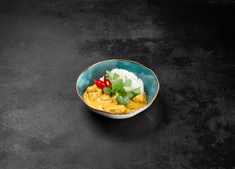 Canvas Print - Traditional indian food. Chicken curry with boiled rice in ceramic bowl on black concrete background. Asian curry with chicken and basmati rice on dark stone table. Hot dish - spicy curry.