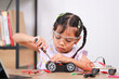 © Narin Sapaisarn - Asian little girl students learn at home by coding robot cars in STEM, STEAM, mathematics engineering science technology computer code in robotics for kids' concepts.