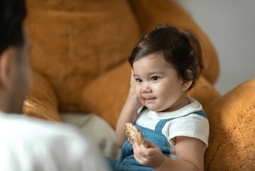 Wall Mural - Cute little toddler holding toy while sitting on floor with stuff toy playing with father at home