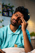 © WESTOCK - Vertical shot of young man suffering headache pain during night at home - concept of tension, health problems and illness.