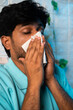 © WESTOCK - Vertical shot of sick man with sneezed using napkin during cold fever at home - concept of influenza, health care and unhealthy