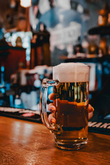 Wall Mural - woman hand bartender hold glass of light beer stands on a table in a bar or pub