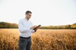 © Serhii - Agronomist inspects soybean crop in agricultural field - Agro concept - farmer in soybean plantation on farm
