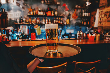 Wall Mural - waiter hand and tray with Beer into glass on bar